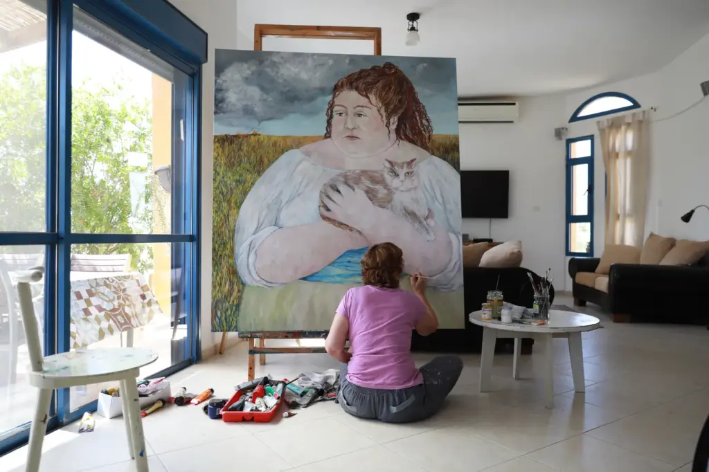 Wide view of the studio, Carolina Arcos in front of a large canvas