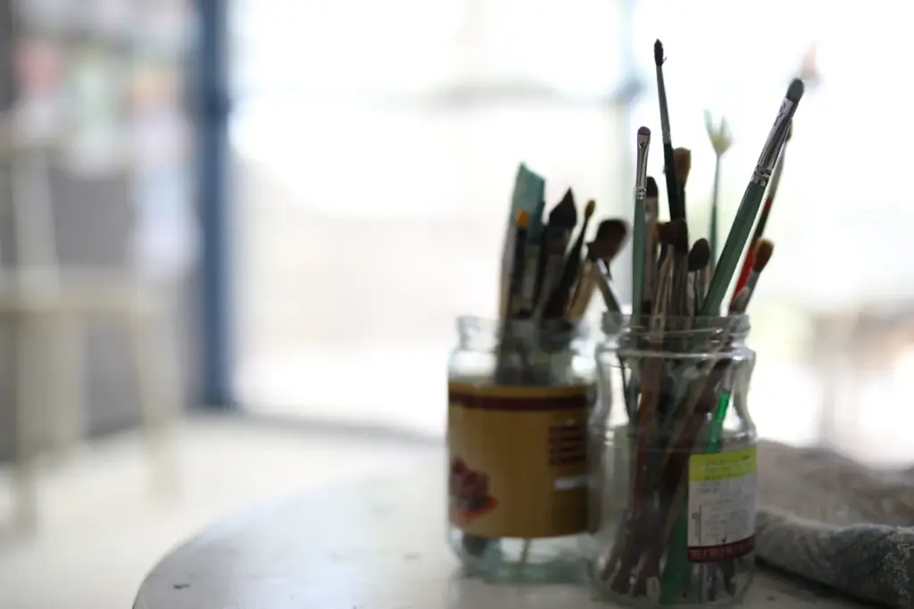 Brushes standing in glass jars by the studio window